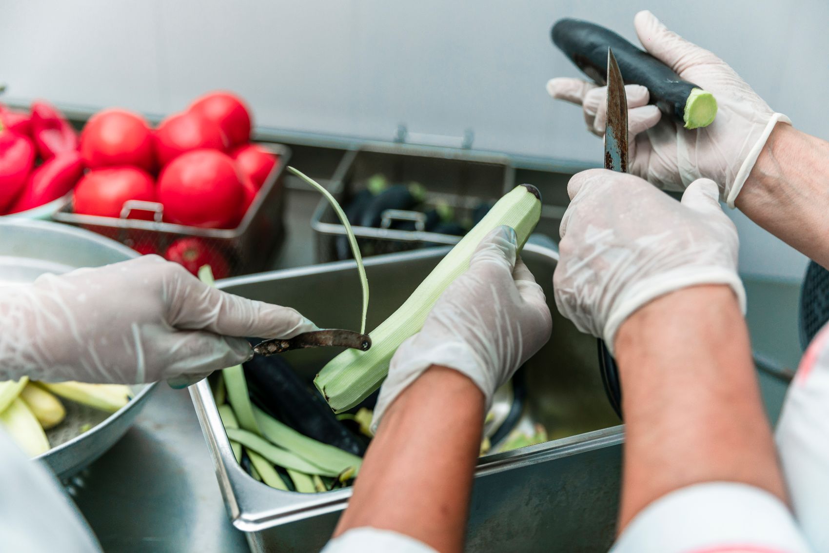 Manos con guantes pelando verduras en cocina